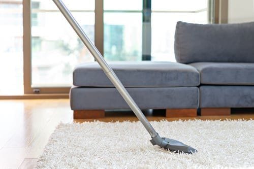 Professional cleaner mopping the floor of a bright, modern Las Vegas living room